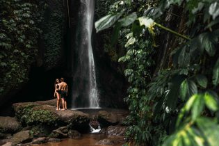 Lovers at the waterfall. Couple admiring a beautiful waterfall in Indonesia. Couple on vacation in Bali. Honeymoon trip. The couple is traveling in Asia. Vacation on the island of Bali with copy space